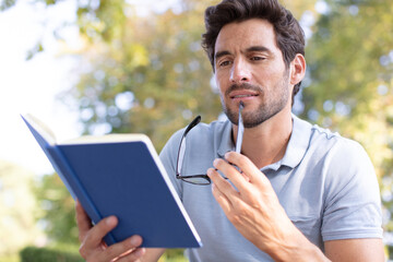 handsomen man reading a book in the park