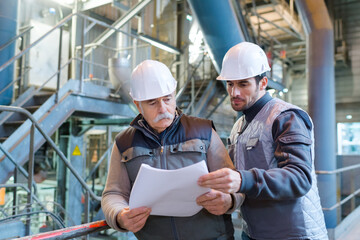 two men looking at paperwork in industrial site