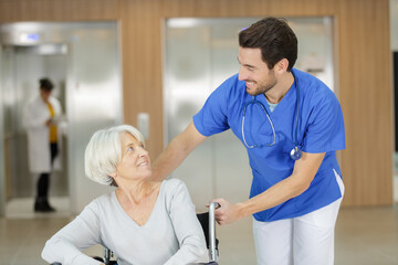 Obraz premium male nurse assisting elderly woman in wheelchair indoors
