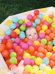 Fototapeta na wymiar One-year-old girl playing in a pool of plastic toy balls