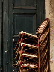 Charming French bistro chairs stacked neatly against a building