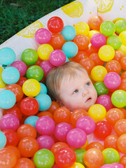 Fototapeta na wymiar One-year-old girl in a vibrant pool of plastic toy balls