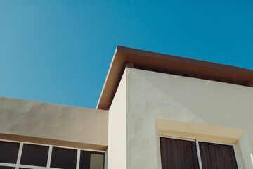 Light casts shadows on a minimalist building against a blue sky.