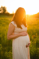 Fototapeta na wymiar Maternity photos of pregnant mom holding baby bump outdoors in nature
