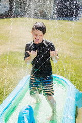 Boy playing with sprinkler during summer