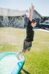 Boy jumping out of pool in yard