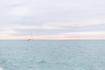 A sailboat on Lake Michigan against a pink streaked morning sky