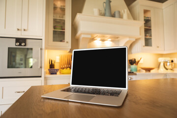 Laptop with blank black screen placed on wooden table at home, copy space