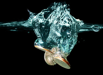 Group of Coins Dropped into Water on Black