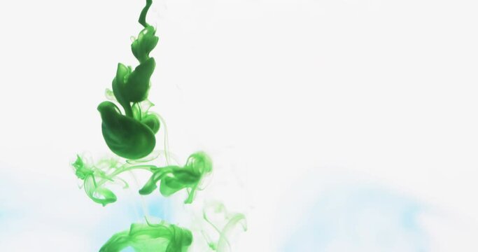 Slow motion video of green watercolor ink mixing in water against grey background