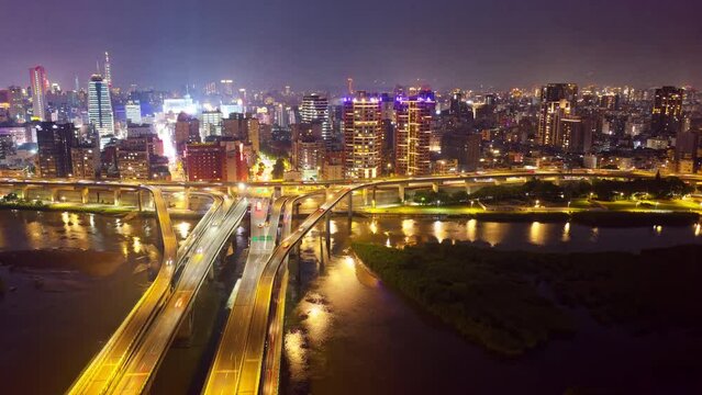 Night view of Zhongxing Bridge over Tamsui River and the riverside Huanhe Expressway in vibrant Taipei City, with a skyline of crowded buildings in Ximending Downtown and 101 Tower in background