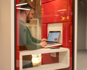 A bearded man in a booth for online negotiations. Privacy booth.
