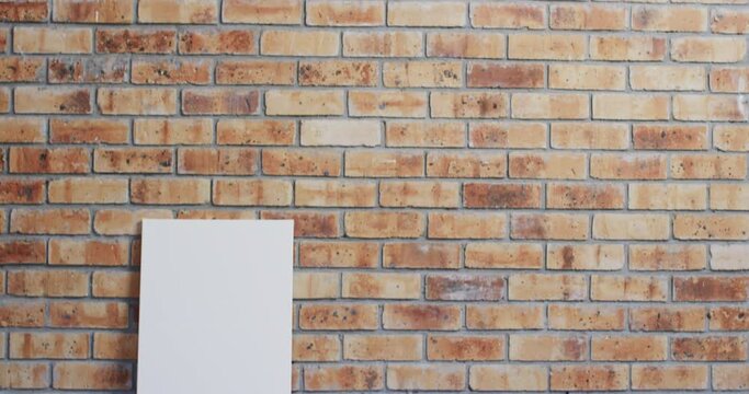 Video of white canvas sign with copy space on floor against brick wall background