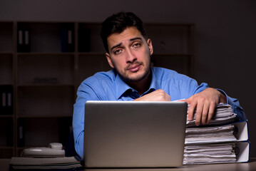 Young male employee working late in the office