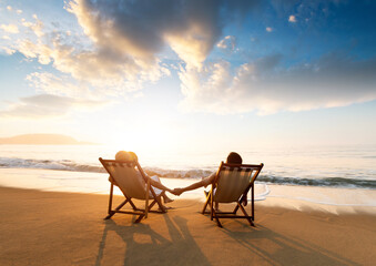 Young couple sunbathing on beach chair - obrazy, fototapety, plakaty