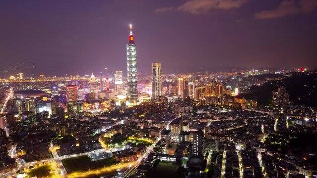 Aerial hyperlapse of Downtown Taipei at night, the vibrant capital city of Taiwan, with 101 Tower standing out amid modern skyscrapers in XinYi Commercial District and city lights dazzling in the dark