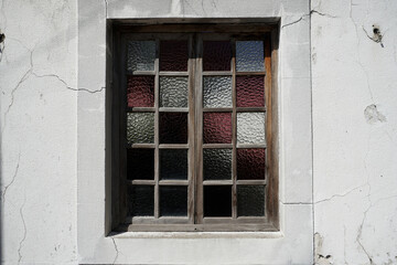 Fototapeta na wymiar Window to the house with stained-glass windows. Cracked white plaster