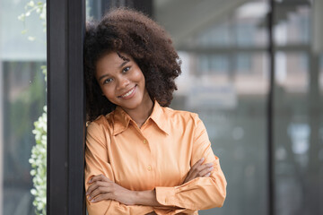 Young pretty African American standing and arms crossed near a window.
