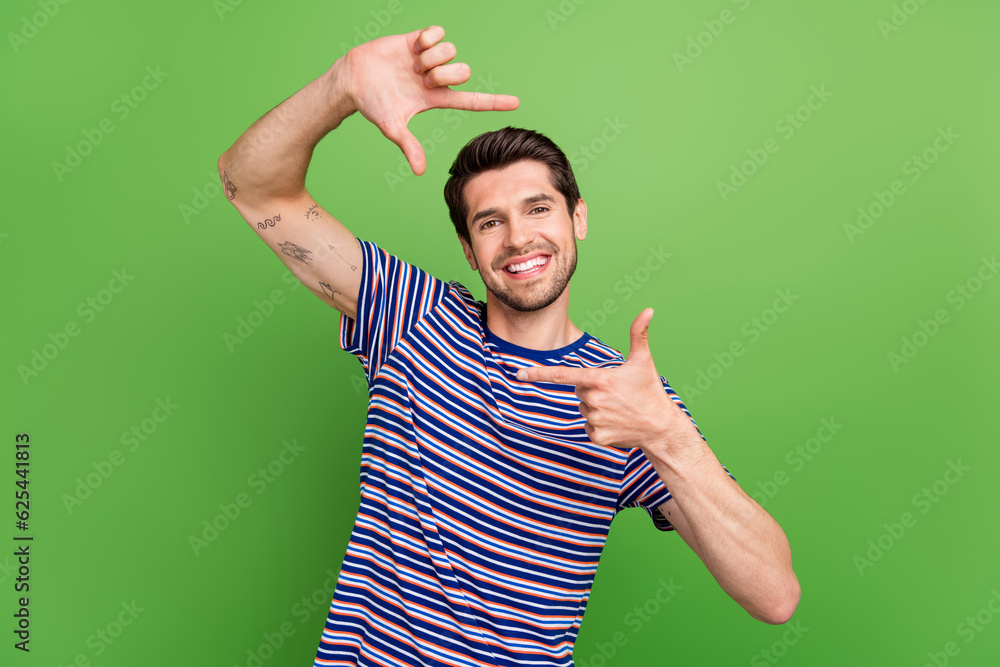 Sticker Portrait of cheerful young guy showing fingers capture frame borders photographing memories have fun isolated on green color background