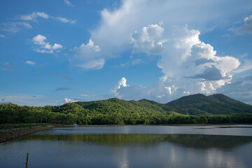 Majestic mountains, cloaked in lush greenery, and blue sky over a quiet reservoir.