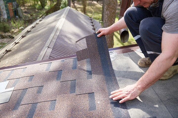 A close-up of the master's hands on the roof mounts flexible tiles.