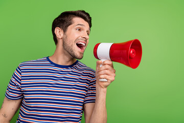 Side photo of funny young positive guy holding megaphone protest activist scream empty space speech...