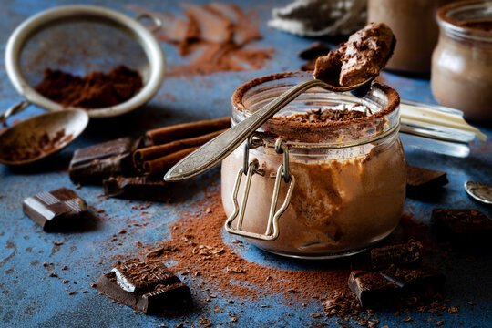 Delicious homemade Chocolate panna cotta or chocolate mousse in a glass jar decorated with cocoa powder and grated dark chocolate