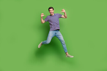 Full length photo of cool excited guy wear striped t-shirt jumping high pointing thumbs himself...