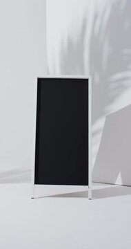 Vertical video of blackboard sign on white stand with copy space on white background