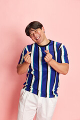 Young korean man in casual clothes standing with smile and positivity, showing gesture of heart against pink studio background. Concept of human emotions, lifestyle, casual fashion, positivity, ad