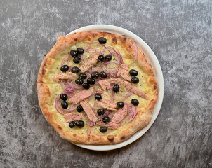 Authentic Neapolitan Italian Pizza: Top-View of Pizza with Black Olives, Tuna, and Mozzarella on a Grey Background with Copyspace