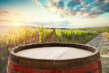 Fototapeta premium Barrel Wineglasses Cheese And Bottle In Vineyard At Sunset . High quality photo