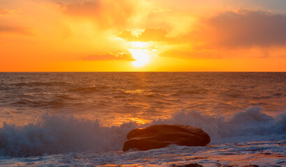 A beautiful sunset over the calm sea with red and orange clouds reflecting in the water