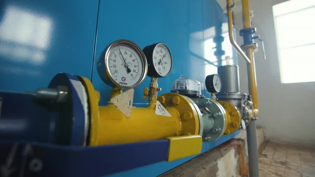 Manometer on yellow pipe checking water pressure in water boiler at hydraulic factory. Hydraulic boiler consisting of pipes and valves