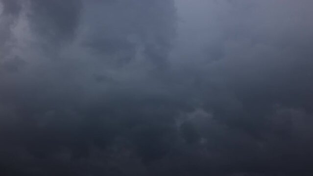Thunderstorms clouds roll at sky. Dark blue storm clouds background, dramatic dark clouds. Time lapse of Storm Clouds motion in the sky. The approach of thunderstorms and rain