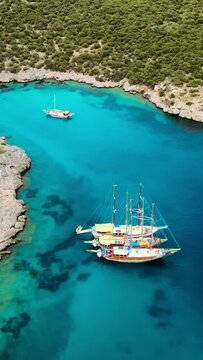 Crystal water sea lagoon and yachts along the Aegean coast. Landscape of turkish riviera nature, vertical shot