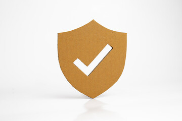 Paper cut of security shield with check mark on white background.