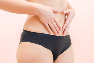 Hands of young woman on her stomach with pink background