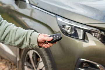 Person with a car key in the hand stands front car. Insurance, loan and buying car concept