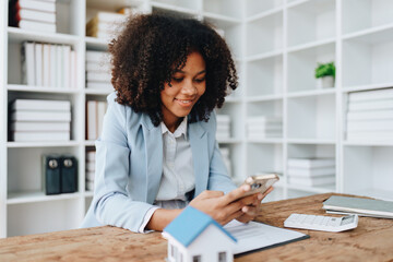 Real estate agent, African American businesswoman Africans use smartphone and calculators to offer mortgages to their clients. Home mortgage and insurance finance concepts