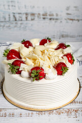 Strawberry and white chocolate cake. Fruit and cream cake on wood background. Close up