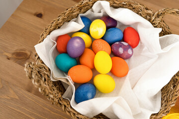 Colorful easter eggs in a basket on a wooden background.
