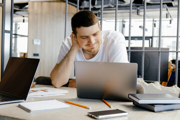 A young guy works on a laptop in the office