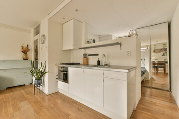 a kitchen and living room in an apartment with wood floors, white cabinets and stainless appliances on the counter tops