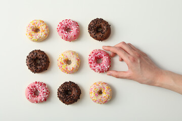Chocolate, white and pink donuts, female hand on white background