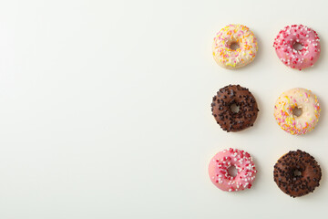 Chocolate, white and pink donuts on white background, space for text