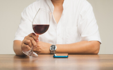 Businessman holding a glass of red wine while sitting at the table.