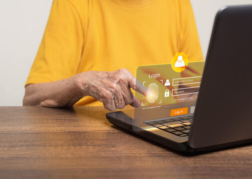 Senior woman login to the network by fingerprint on the virtual screen from a laptop while sitting at the table