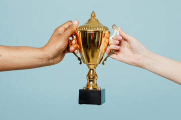 Close up cropped male holding in hand golden cup of football sport team isolated on pastel plain...