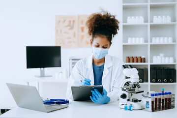 Modern medical research laboratory. African female scientist working with micro pipettes analyzing...